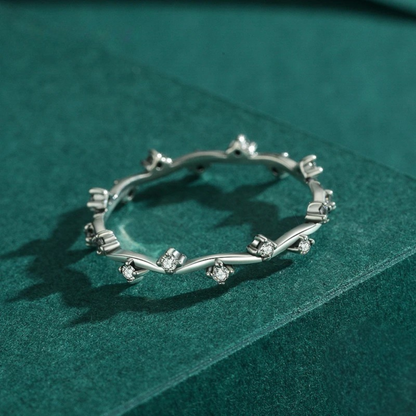 Delicate silver ring with twisting vine-like structure and small clear stones

