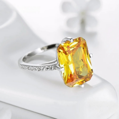 Silver ring with large rectangular yellow gemstone and pavé band detail

