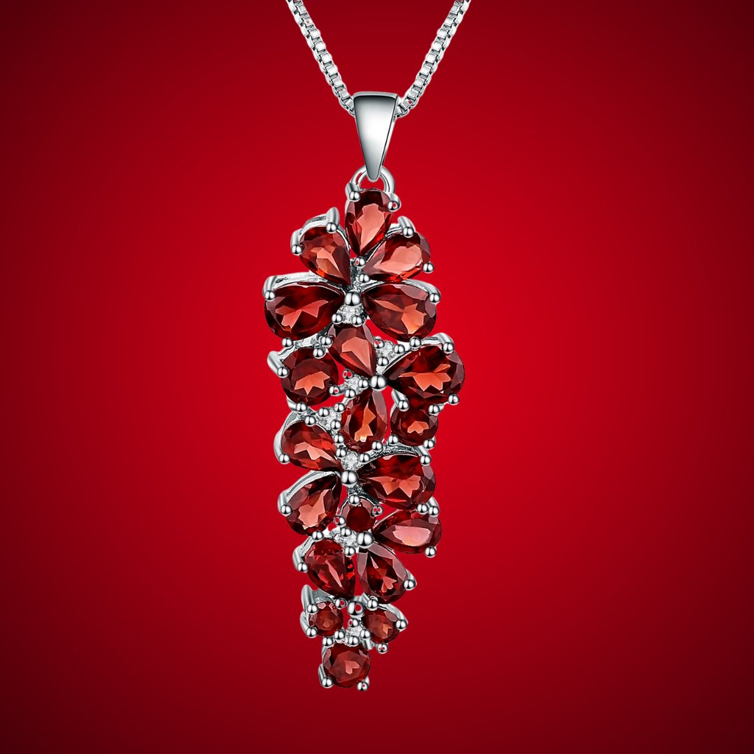 Cluster pendant necklace with deep red gemstones arranged in floral shapes, set in polished silver.

