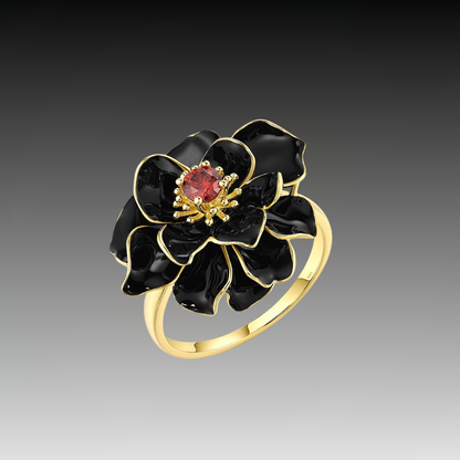 Gold ring with layered black enamel flower petals and a red gemstone at the center.

