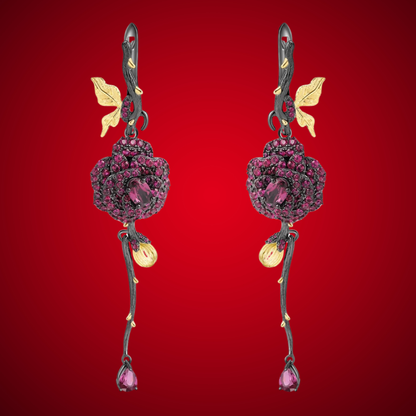 Long black rose earrings with red gemstones, gold leaves, and bud details from the Rossa Collection.

