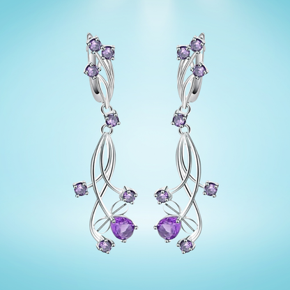Sterling silver drop earrings shaped like violet enamel flowers with layered petals and small clear gemstones at the center