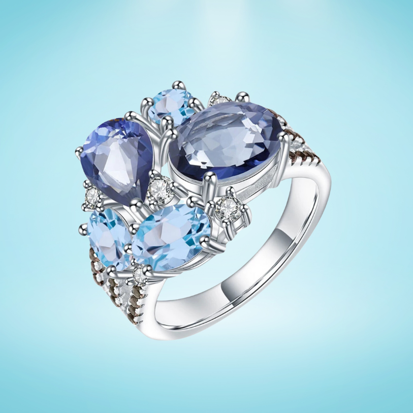 Silver ring featuring an asymmetric cluster of blue and violet gemstones in various cuts

