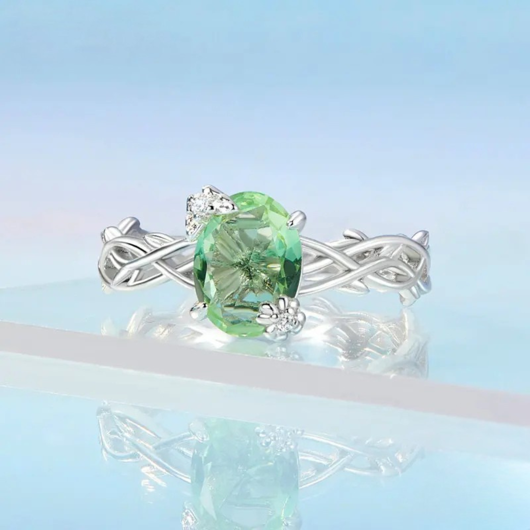 Silver ring with green round gemstone and vine-inspired band design

