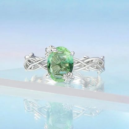 Silver ring with green round gemstone and vine-inspired band design

