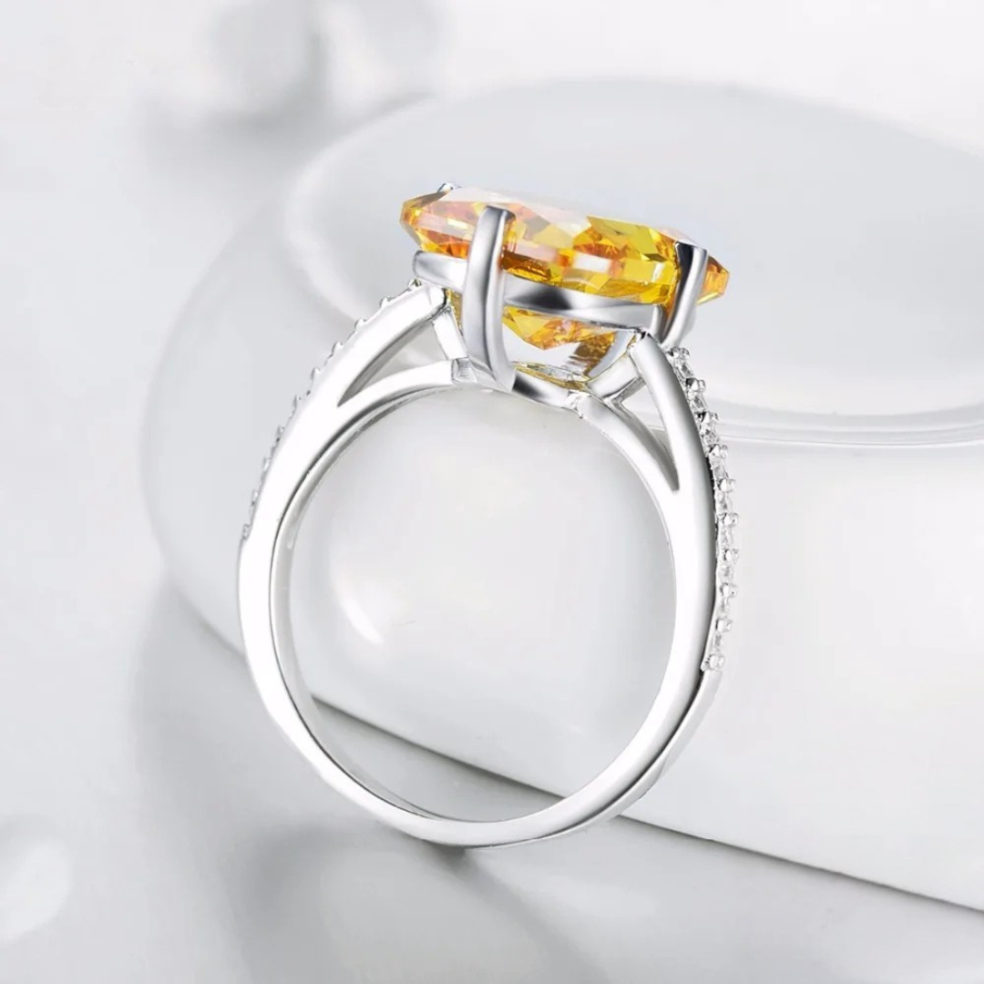 Silver ring with large rectangular yellow gemstone and pavé band detail

