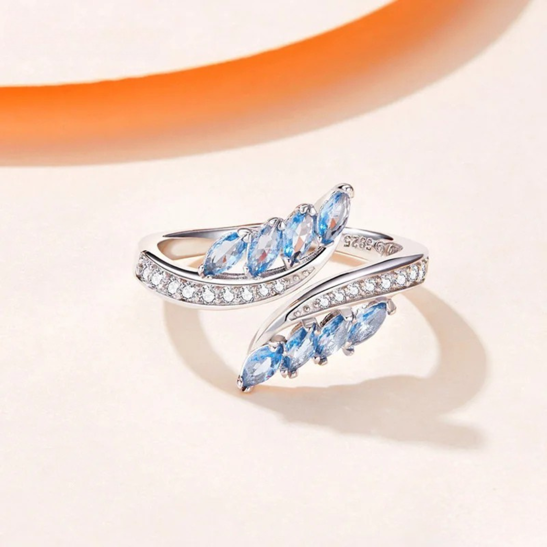 Silver ring featuring marquise-cut blue stones and a row of white cubic zirconia.

