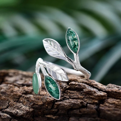 Adjustable silver ring featuring green marbled leaf accents in an open branch design.

