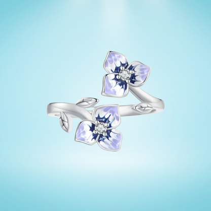 Sterling silver wrap ring featuring two delicate purple and white enamel flowers with clear center stones and leaf details.

