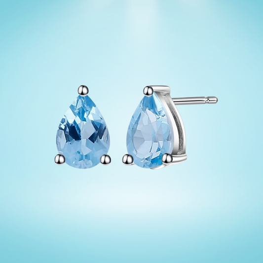 Sterling silver stud earrings with pear-shaped blue topaz gemstones in a three-prong setting

