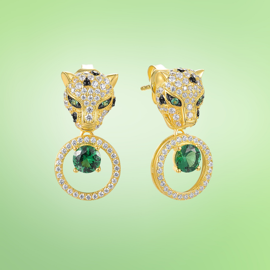 Gold earrings with panther head design, sparkling black and white stones, and green gemstone drop in circular setting

