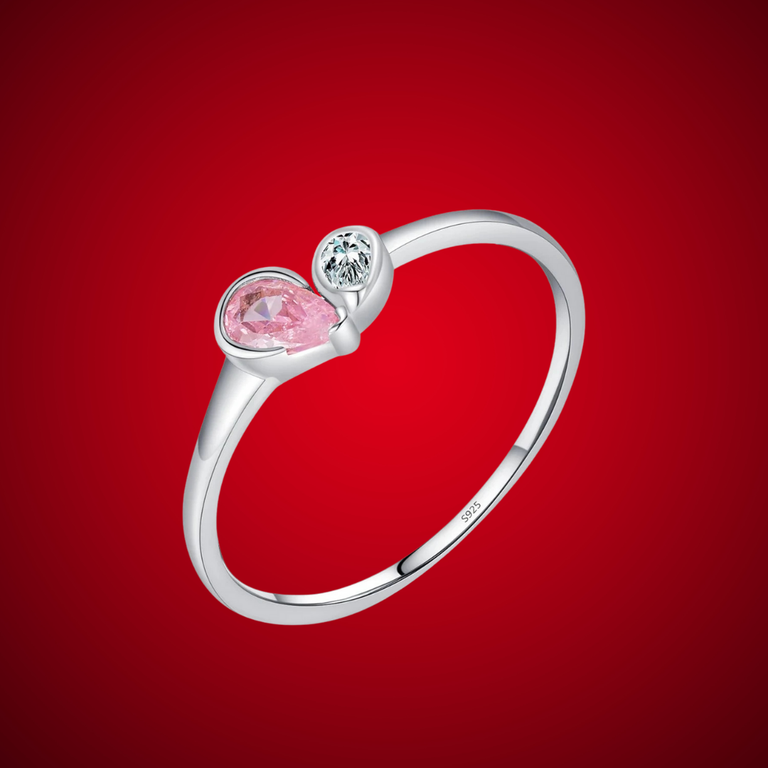 Sterling silver ring featuring a pink teardrop stone paired with a round clear stone in an open-heart inspired setting.

