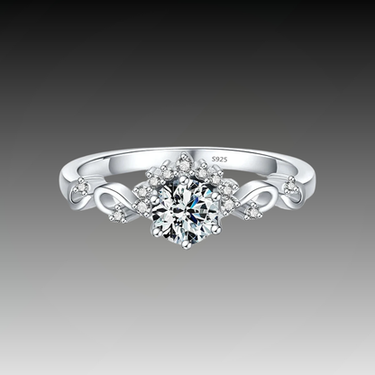 Silver ring with a central round-cut stone surrounded by delicate side diamonds and twisted vine-like detailing.

