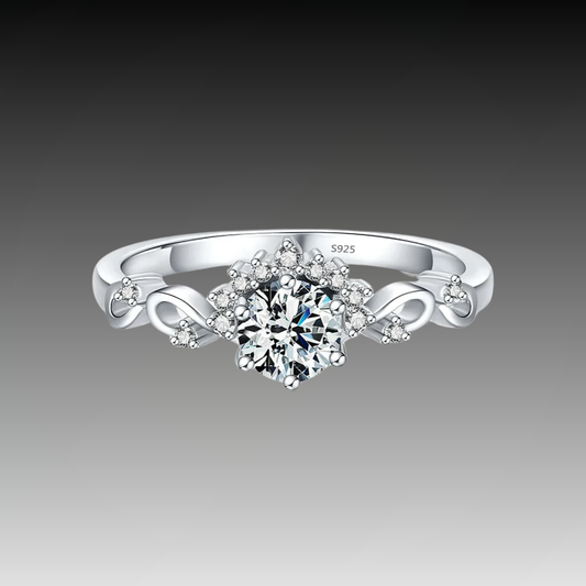 Silver ring with a central round-cut stone surrounded by delicate side diamonds and twisted vine-like detailing.

