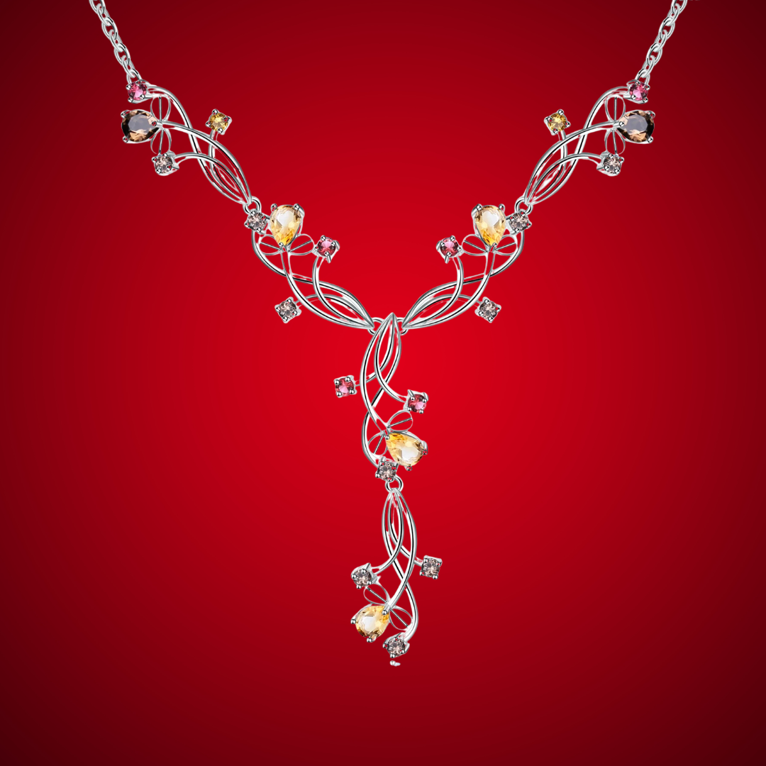 Silver necklace with an intricate swirling design, adorned with multicolored gemstones in pink, yellow, brown, and clear tones.

