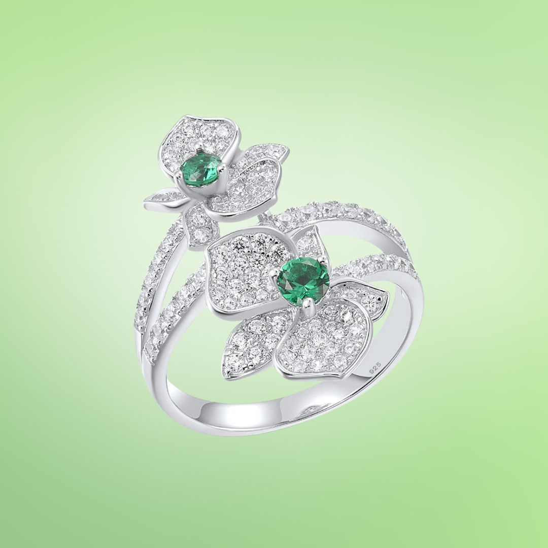 Sterling silver ring with twin pavé-set floral forms and vivid green center stones

