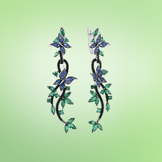 Long silver earrings with blue butterfly and green leaf gemstone detailing

