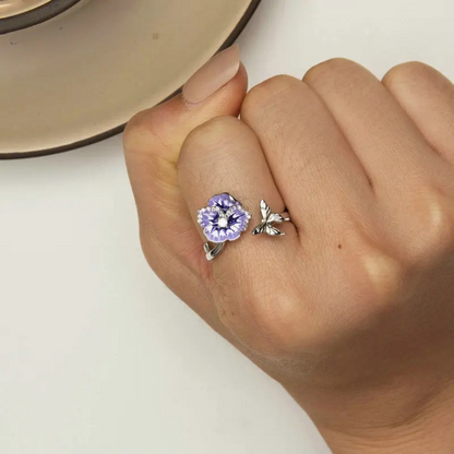 Sterling silver wrap ring featuring two delicate purple and white enamel flowers with clear center stones and leaf details.

