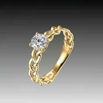 Gold ring with a braided band design and a round-cut clear central stone in a four-prong setting.

