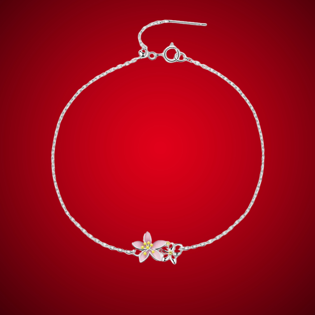 Delicate silver bracelet featuring two small pink cherry blossom charms on a fine chain.

