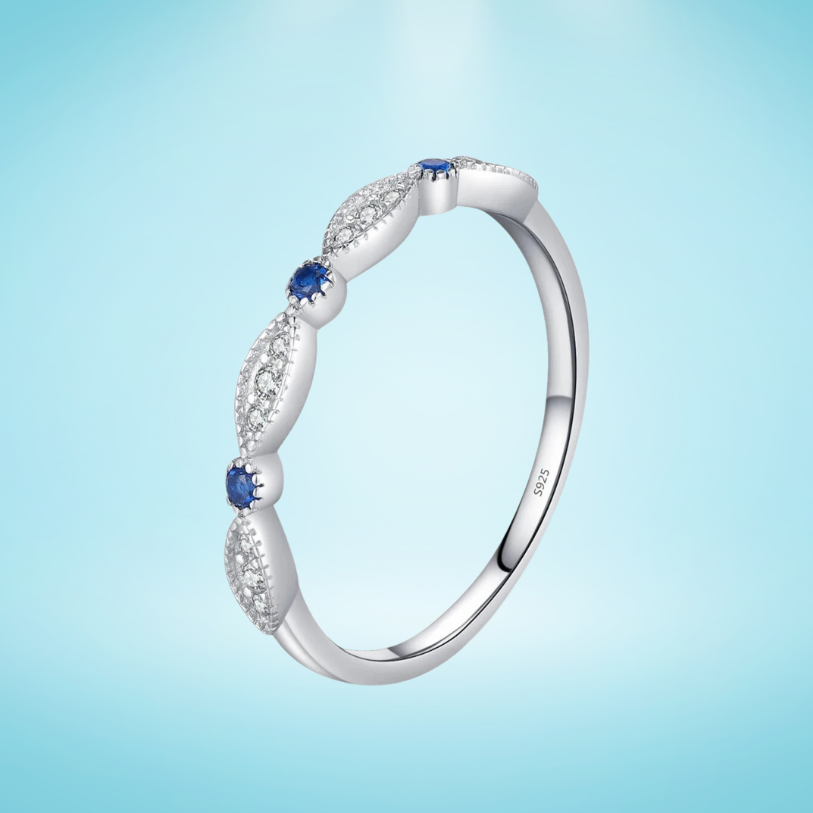 Sterling silver band with alternating marquise shapes and small round blue and clear stones

