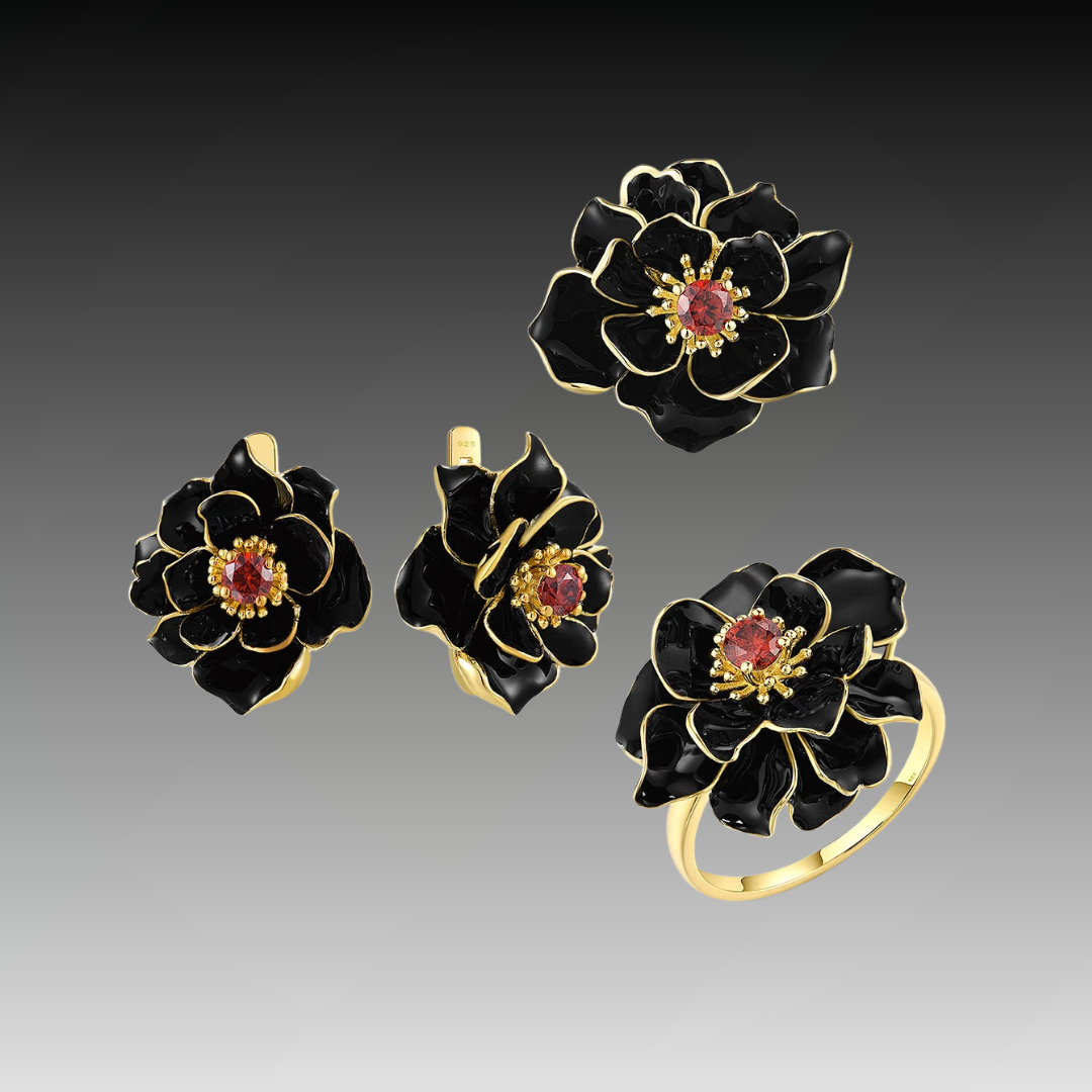Jewelry set with black enamel floral design and red gemstone center, including a ring, earrings, and pendant.

