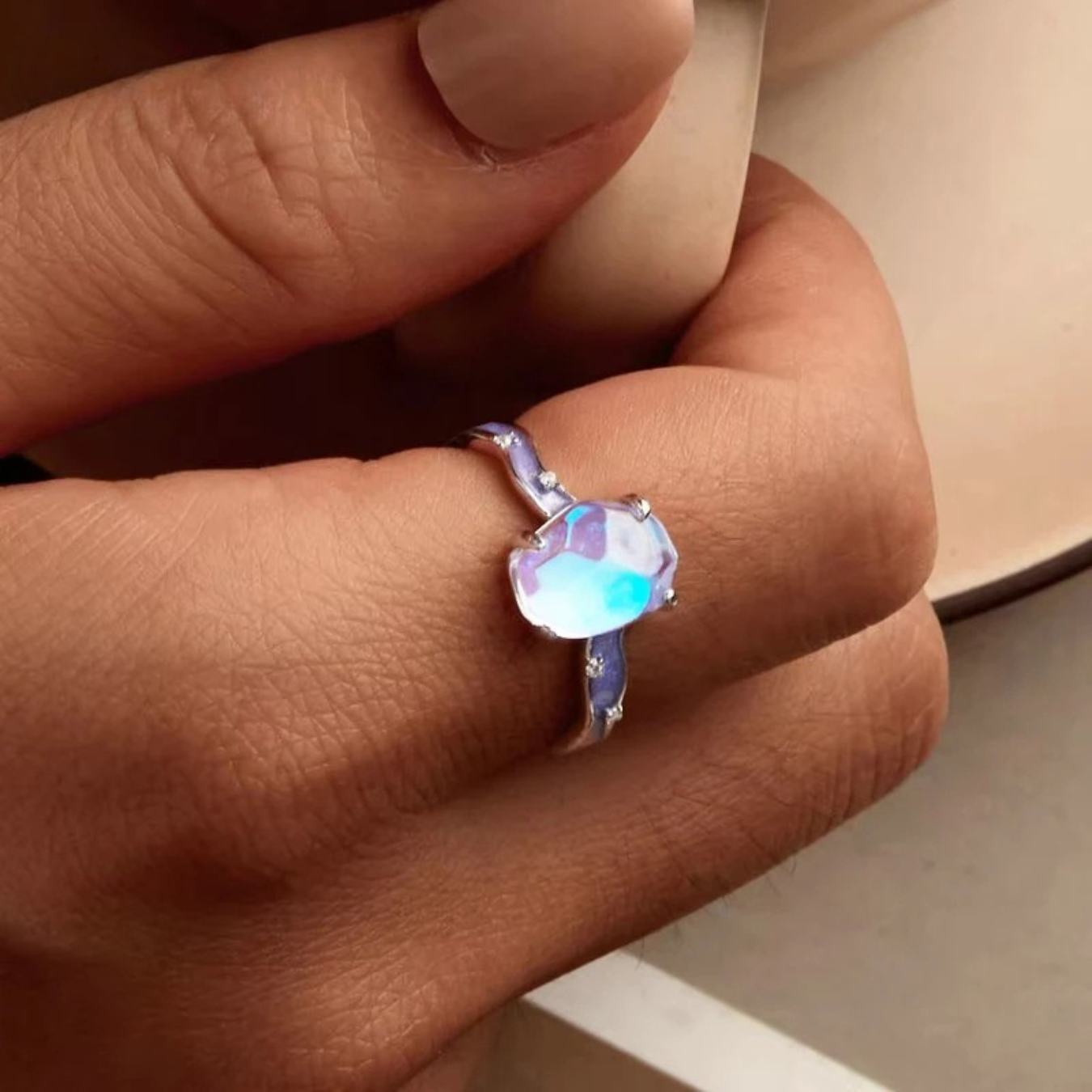 Close-up of a hand wearing a ring with a colorful gemstone.