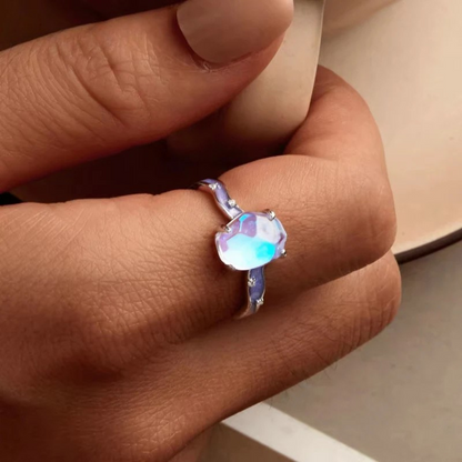 Close-up of a hand wearing a ring with a colorful gemstone.