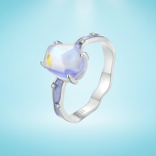 Silver ring with a heart-shaped gemstone on a light blue background