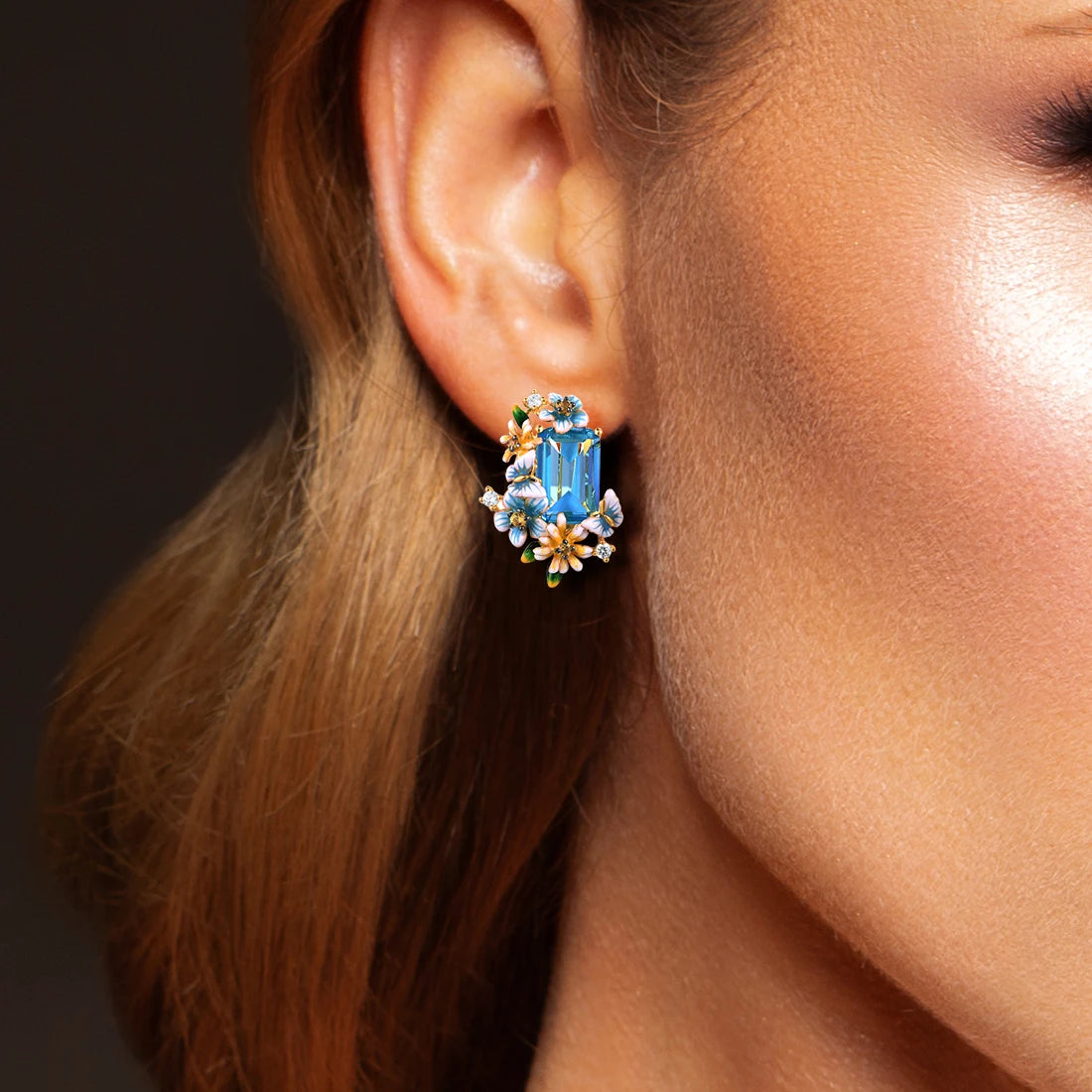 Gold floral earrings with large blue emerald-cut stones and pastel enamel blossoms

