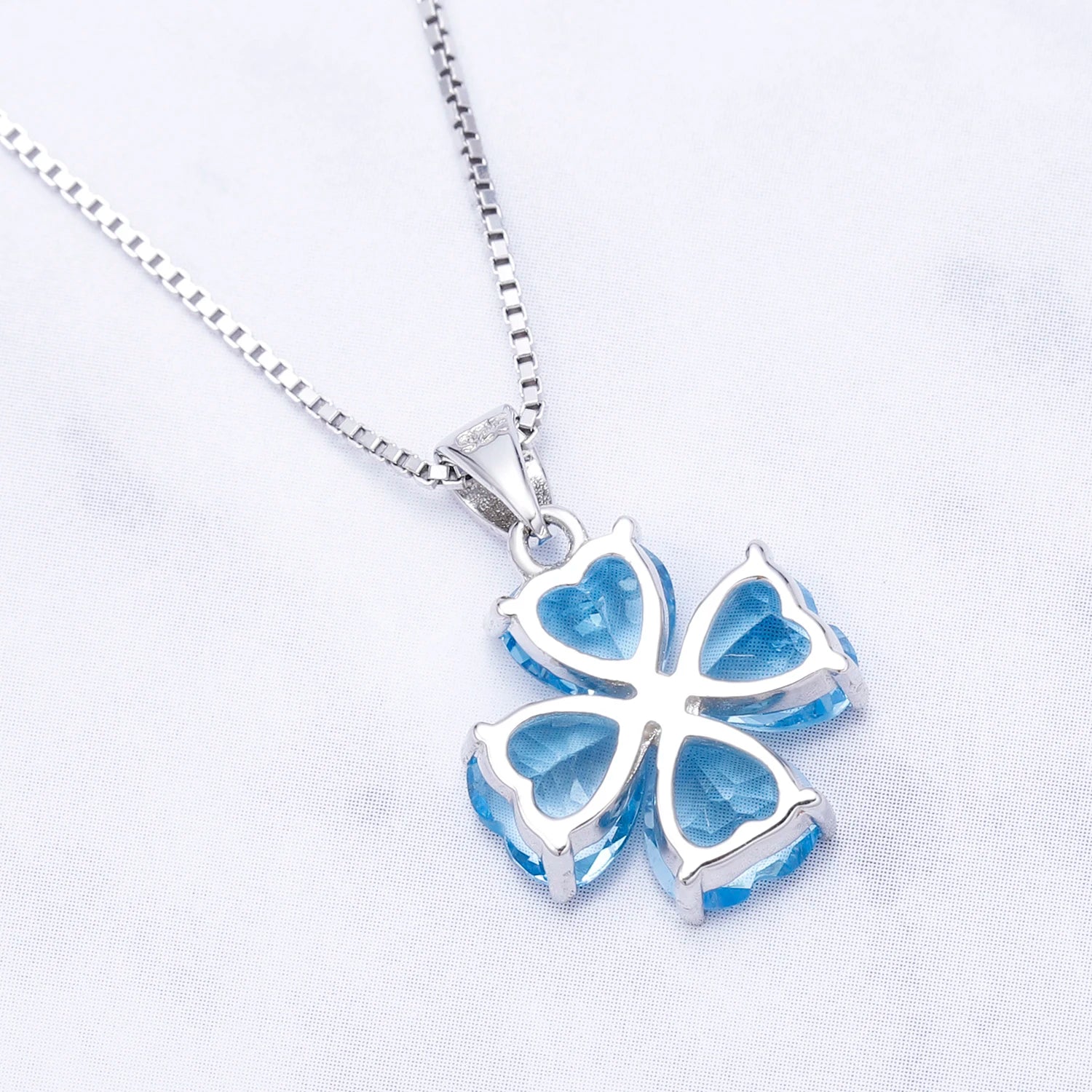 Silver pendant featuring four heart-cut light blue stones arranged in a floral shape

