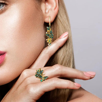Gold butterfly ring adorned with green crystals and delicate flower accents

