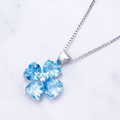 Silver pendant featuring four heart-cut light blue stones arranged in a floral shape


