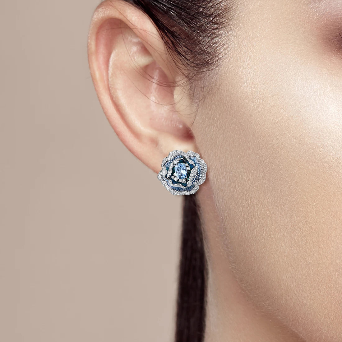 Silver and blue enamel rose-shaped earrings with layered petals and central light blue gemstones


