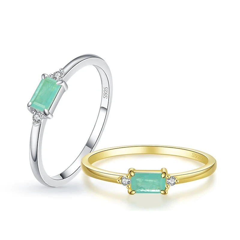 Delicate gold ring with a rectangular light green stone and two small clear side stones.

