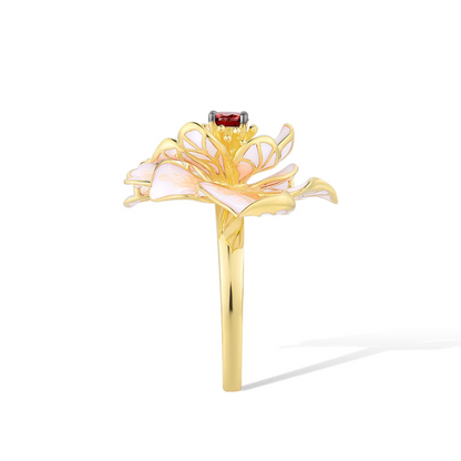 Gold ring with layered white enamel flower petals and a red gemstone at the center.

