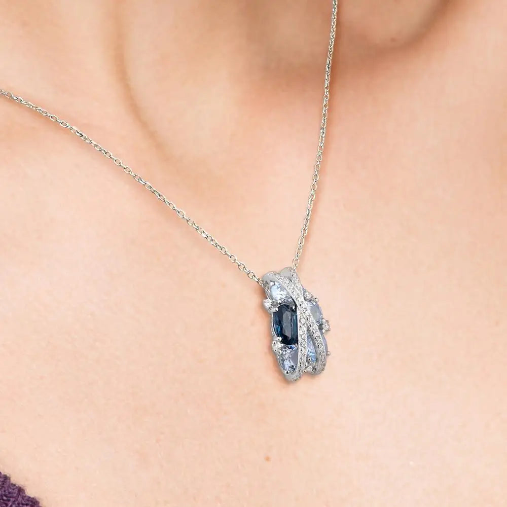 Sterling silver jewelry piece featuring crisscross pavé bands over clustered light and dark blue gemstones