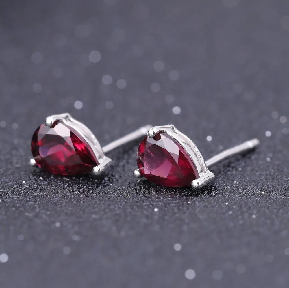 Pear-cut red gemstone stud earrings set in silver-tone prongs.

