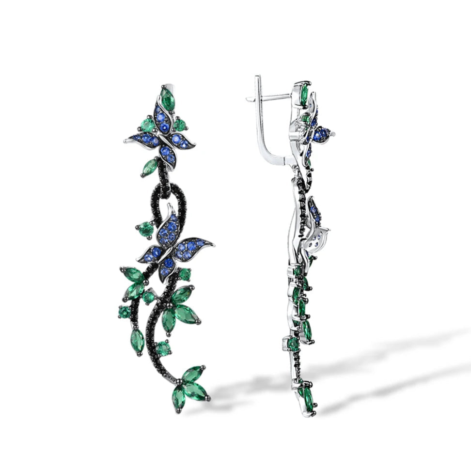 Long silver earrings with blue and green crystal butterflies and vine-like detailing

