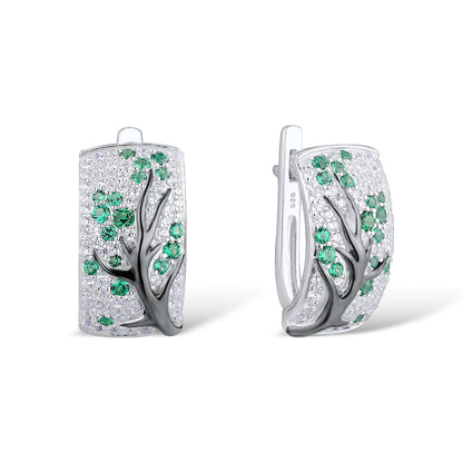 Silver earrings with raised black tree branches and scattered green and white stones

