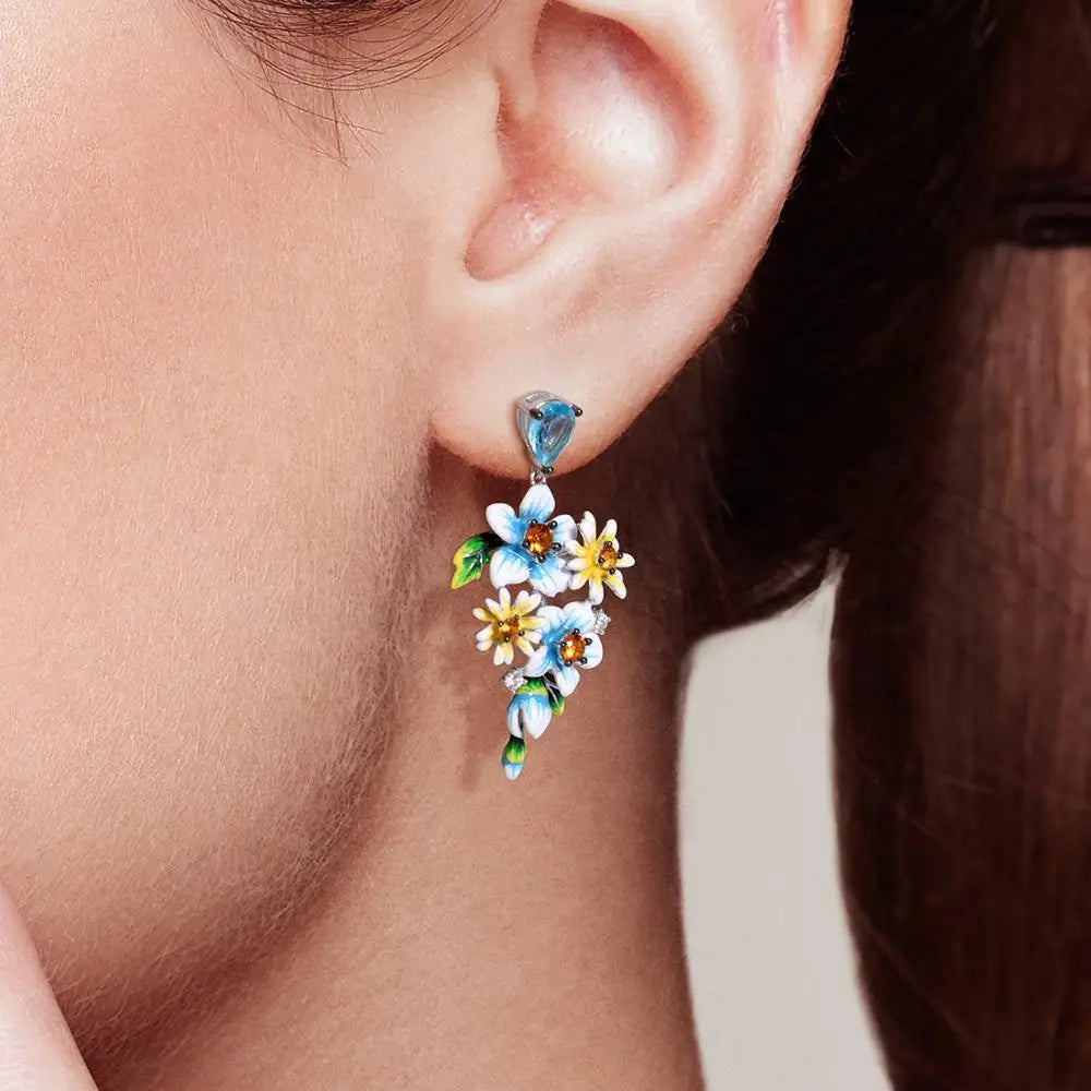 Sterling silver floral drop earrings with blue enamel flowers and orange gemstone centers


