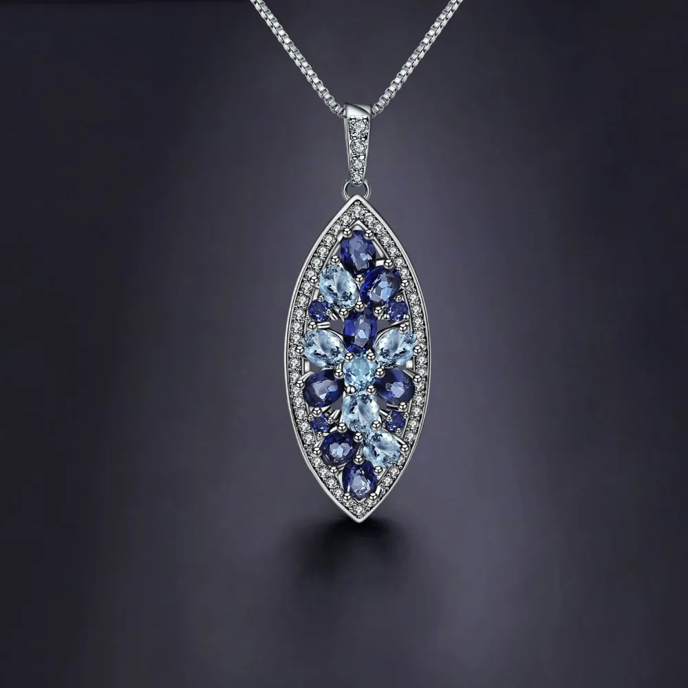 Marquise-shaped silver pendant with a floral arrangement of light and dark blue gemstones

