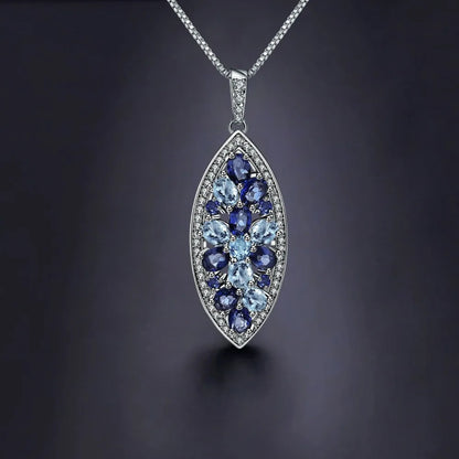Marquise-shaped silver pendant with a floral arrangement of light and dark blue gemstones

