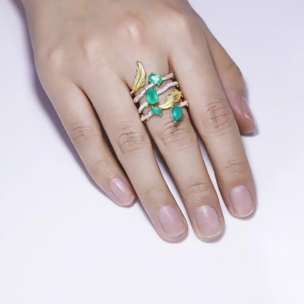 Multi-band silver ring with green gemstones, gold leaf accents, and intricate vine-like detailing

