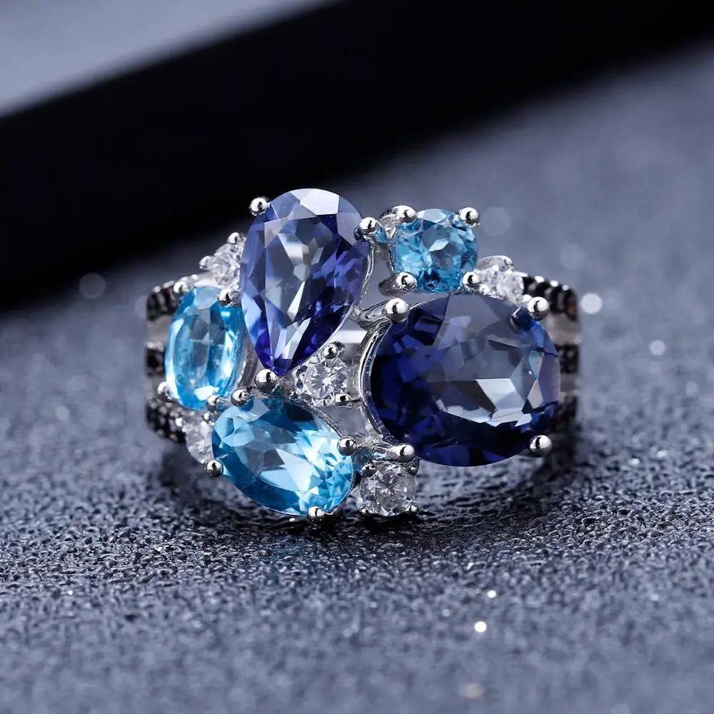 Silver ring featuring an asymmetric cluster of blue and violet gemstones in various cuts

