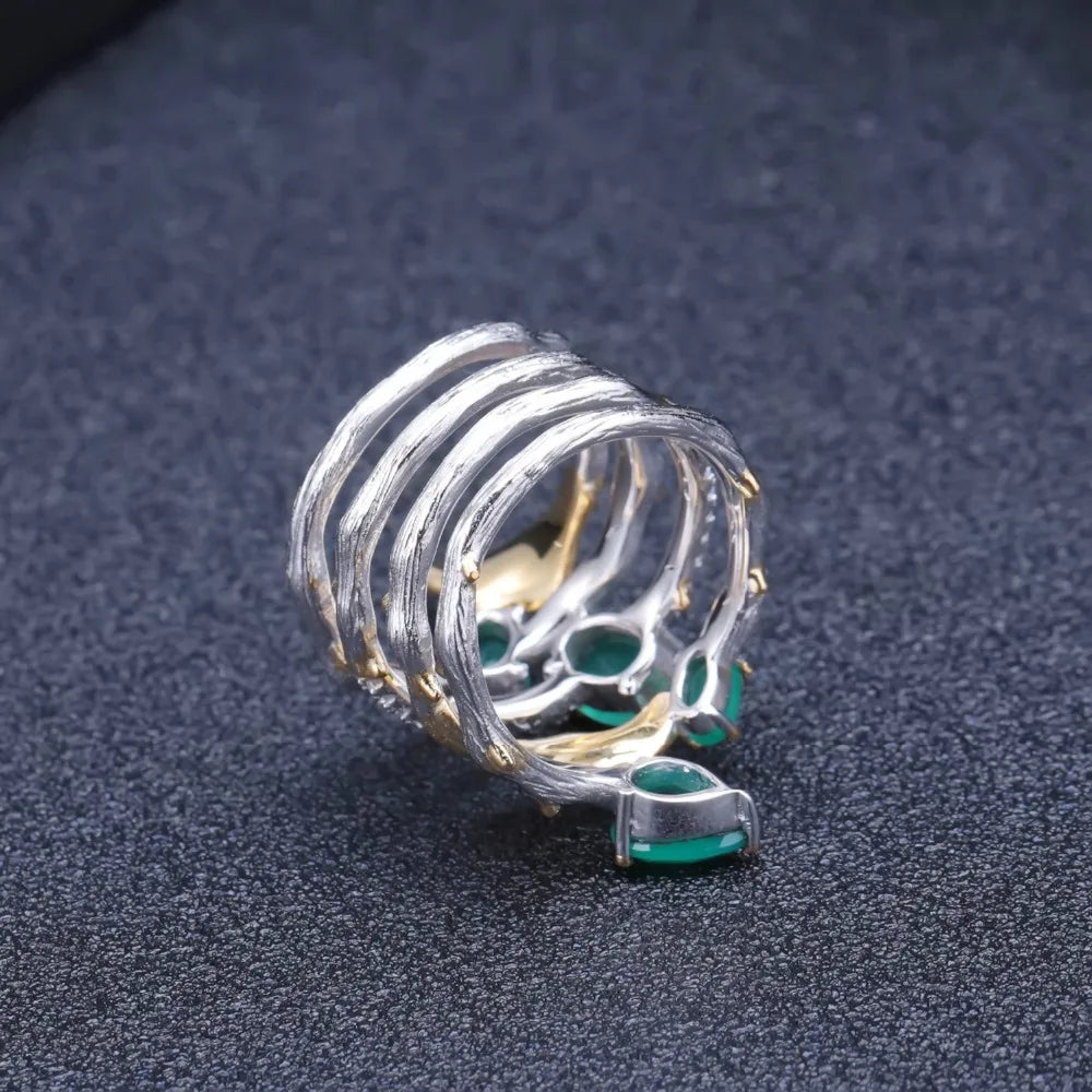 Multi-band silver ring with green gemstones, gold leaf accents, and intricate vine-like detailing

