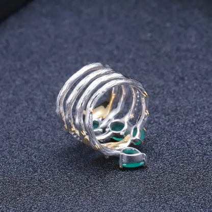 Multi-band silver ring with green gemstones, gold leaf accents, and intricate vine-like detailing

