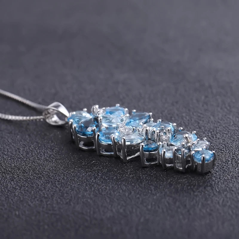 Silver pendant featuring a cascading cluster of mixed-cut blue gemstones in varying tones

