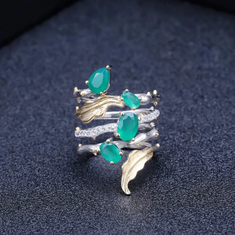 Multi-band silver ring with green gemstones, gold leaf accents, and intricate vine-like detailing


