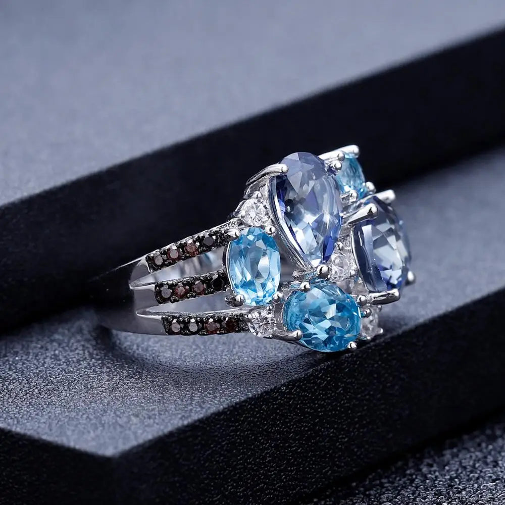 Silver ring featuring an asymmetric cluster of blue and violet gemstones in various cuts

